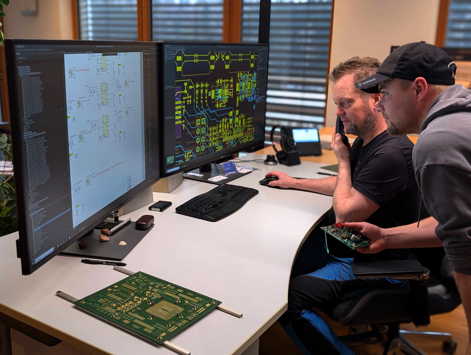 Zwei Entwickler bei ConSYtronic vor Schaltplan und Layout, mit bestückter Baugruppe in der Hand